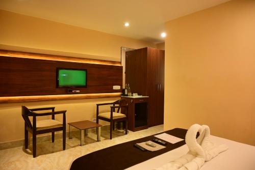 a hotel room with a tv and a bed and chairs at Hotel Haywizz in Port Blair
