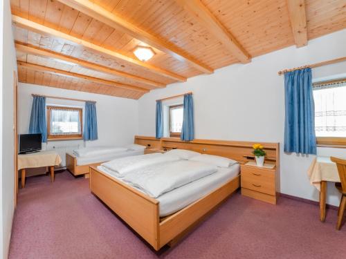 a bedroom with a large bed and a desk at Garnì La Grambla in Selva di Val Gardena