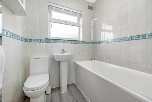 a bathroom with a toilet and a tub and a sink at Stunning 3BR House w Garden & Parking in Richmond in Kew Gardens