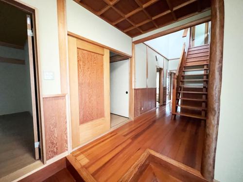 a hallway with wooden floors and stairs in a house at シークレットベースゆふいん in Yufuin