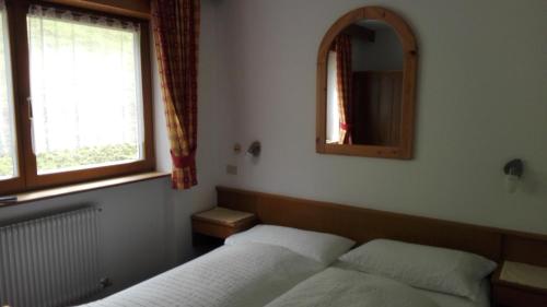 a bedroom with two beds and a mirror at Garnì La Grambla in Selva di Val Gardena