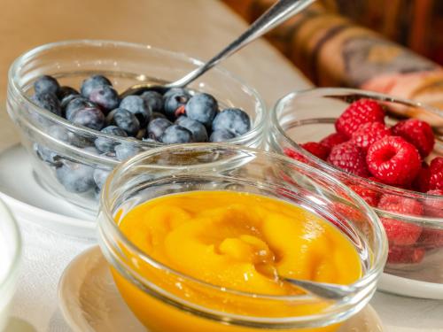 a table with two bowls of fruit and a bowl of berries at Garnì La Grambla in Selva di Val Gardena