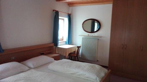 a bedroom with a bed and a mirror and a window at Garnì La Grambla in Selva di Val Gardena