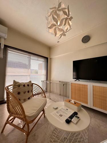 a living room with a tv and a chair and a table at 白浜バケーションレンタル　SVR in Shirahama