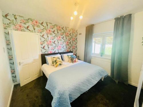 a small bedroom with a bed with a floral wallpaper at Mitchell Apartment by Klass Living Coatbridge in Coatbridge