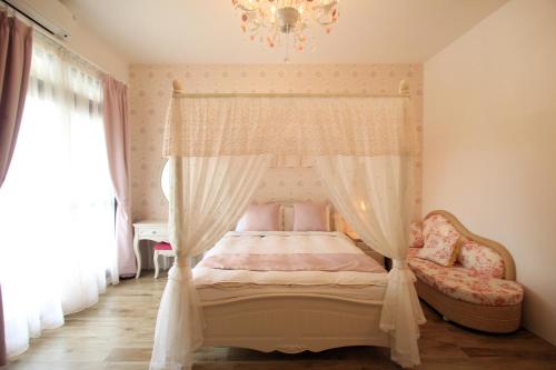 花蓮市的住宿－齊亞風情，一间卧室配有一张天蓬床和吊灯。