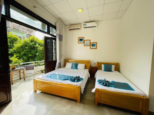 a bedroom with two beds and a large window at SHARK HOSTEL in Hue