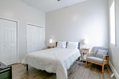 a white bedroom with a bed and a chair at Newly Renovated Downtown Apartment in the Historic District, Quiet Street! in Mobile