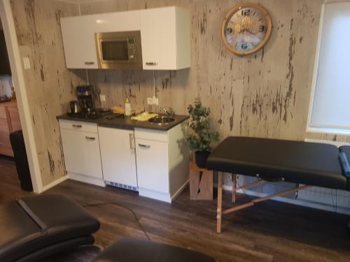 una cocina con armarios blancos y un reloj en la pared en H15, Sauna- en Wellnesschalet geschikt voor 2 personen en Epe