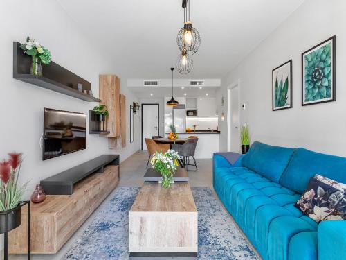 a living room with a blue couch and a table at Lovely first floor apartment, heating pool ! in Playa Flamenca