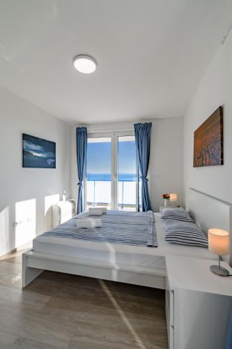 a white bedroom with a large bed with blue curtains at Villa Miri III in Privlaka