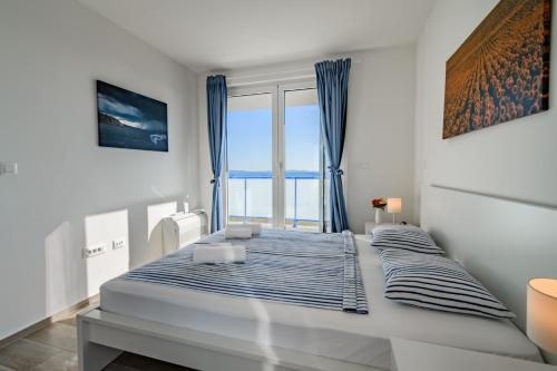 a white bedroom with a large bed with blue curtains at Villa Miri III in Privlaka