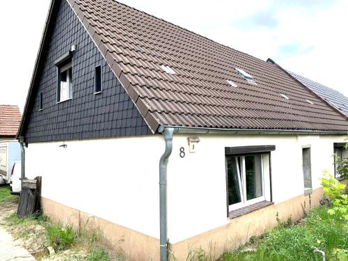 een wit huis met een zwart dak bij Haus Linde in Biesenthal
