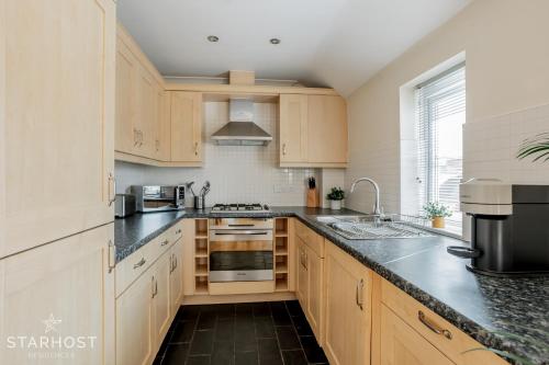 a kitchen with wooden cabinets and black counter tops at StarHost Residences - Smart 2 Bedroom Apartment in Newbury in Newbury