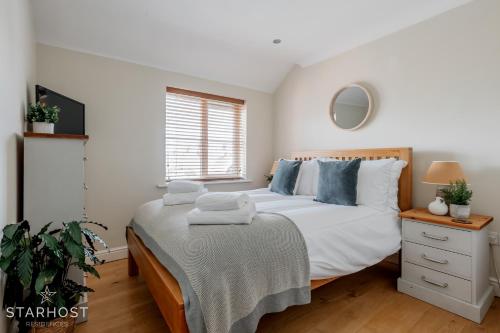 a bedroom with a bed with white sheets and blue pillows at Smart 2 Bedroom Apartment in Newbury in Newbury
