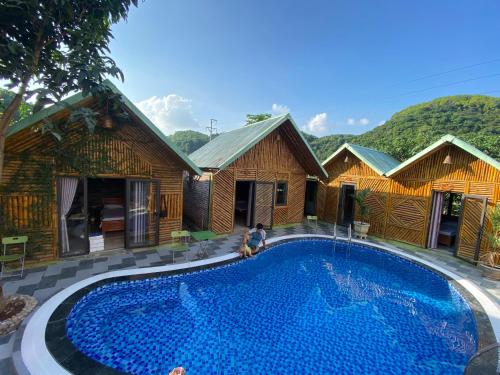 a resort with a large swimming pool in front of some buildings at Cat Ba Rustic Homestay in Cat Ba