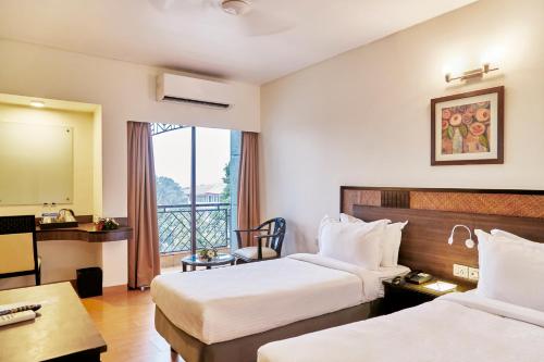 a hotel room with two beds and a balcony at Hotel Orion Centrally near North Goa & Panjim in Porvorim