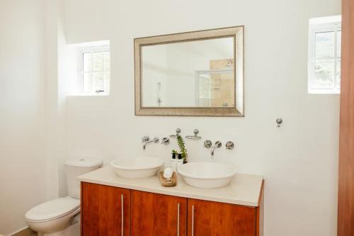 开普敦Avisa Villa - 4 bedroom Villa with Majestic Ocean Views的带两个水槽、一个马桶和一面镜子的浴室