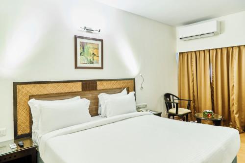 a bedroom with a large white bed and a chair at Hotel Orion Centrally near North Goa & Panjim in Porvorim