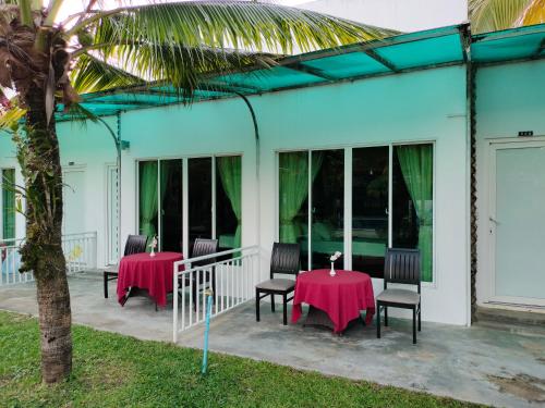 a patio with two tables and chairs and a palm tree at Twin Palms Resort in Sihanoukville