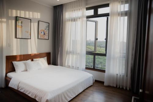 a bedroom with a bed and a large window at SEN VILLA Boutique in Bao Loc