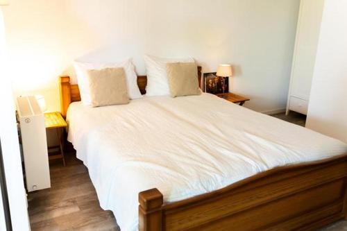 een slaapkamer met een groot bed met witte lakens en kussens bij Luxe prive-kamer - studio in villa aan zee, Dishoek, vernieuwd in Dishoek