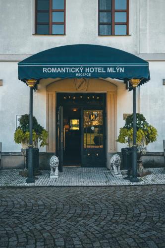 a hotel with a blue awning in front of a building at Romantic Hotel Mlýn Karlstejn in Karlštejn