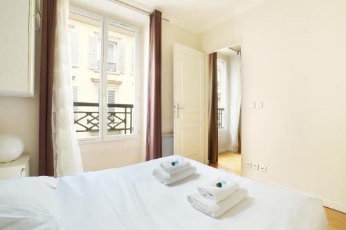 une chambre avec un lit blanc avec des serviettes dessus dans l'établissement Pick A Flat's Apartments in Batignolles - Rue Biot, à Paris