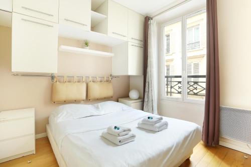 une chambre avec un lit blanc avec des serviettes dessus dans l'établissement Pick A Flat's Apartments in Batignolles - Rue Biot, à Paris