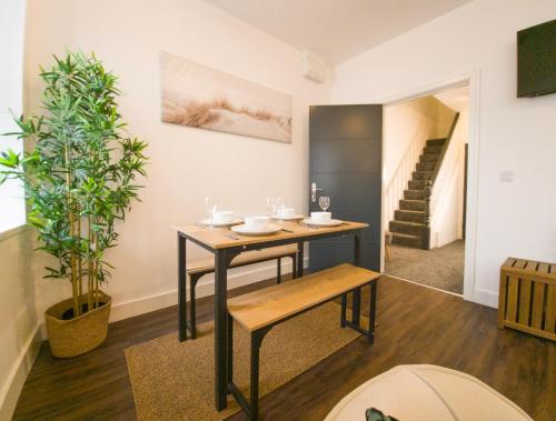 a dining room with a table and a plant at Principality Suites; Three Bed By Property Promise in Cardiff