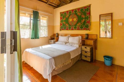 ein Schlafzimmer mit einem Bett und einem Wandgemälde in der Unterkunft African Sunsets (Bophirimo Self-Catering Guest House) in Kasane