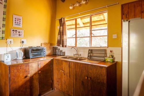 a kitchen with wooden cabinets and a sink and a window at African Sunsets (Bophirimo Self-Catering Guest House) in Kasane