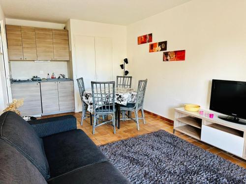 un salon avec un canapé et une table avec des chaises dans l'établissement Le Pré - Port Fréjus, bord de Mer et Base Nature, à Fréjus