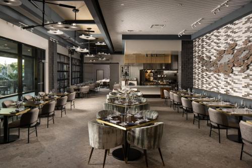 a restaurant with tables and chairs and a kitchen at Luminary Hotel & Co., Autograph Collection in Fort Myers