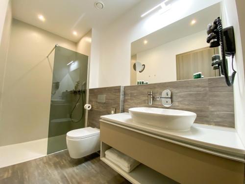 ein Badezimmer mit einem Waschbecken, einem WC und einem Spiegel in der Unterkunft ARUS Hotels in Hamburg