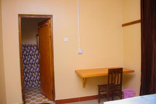 um quarto com uma mesa de madeira e um quarto com uma porta em Margareth's Home Stay Free Wi-Fi and Tv em Tanga