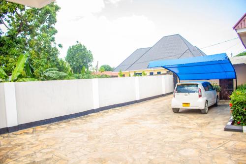 una macchina bianca parcheggiata in un parcheggio vicino a una recinzione di Margareth's Home Stay Free Wi-Fi and Tv a Tanga