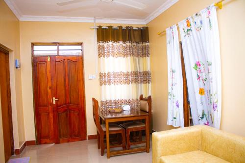 een woonkamer met een tafel en een deur bij Margareth's Home Stay Free Wi-Fi and Tv in Tanga