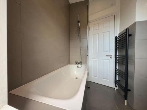 eine weiße Badewanne im Bad mit Tür in der Unterkunft Star London Warwick Mansions 3-Bed Haven in London