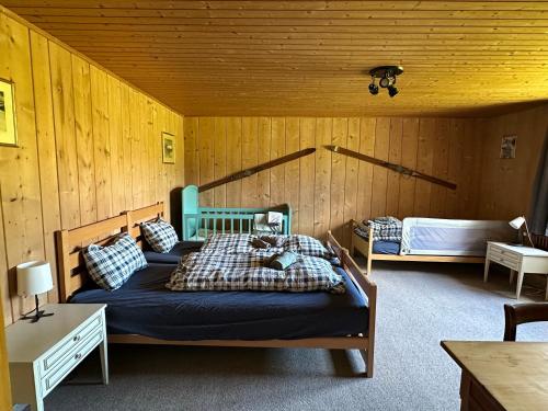 een slaapkamer met 2 bedden in een houten kamer bij Idyllisch gelegene grosszügige Ferienwohnung Chumma in Frauenkirch