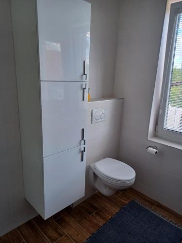 a white bathroom with a toilet and a window at Apartmán Radenice 