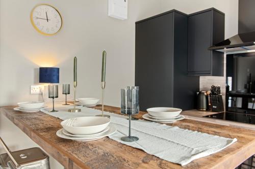 a kitchen with a wooden table with plates and bowls at Brand New 1-Bed Flat With Free Parking in Nottingham