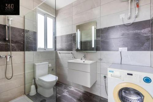 Un baño con inodoro, lavabo y espejo. en Central & Spacious Penthouse w/ 1BR + City View by 360 Estates, en Msida