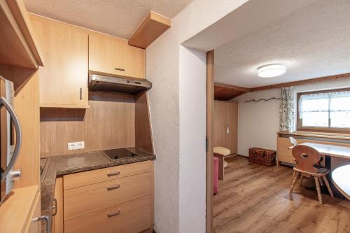 una cocina con armarios de madera y una mesa con una silla en Hauseggerhof en Längenfeld
