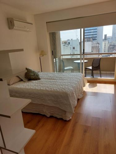 a bedroom with a bed and a balcony with a view at Amplio departamento, piso alto, luminoso ! in Buenos Aires