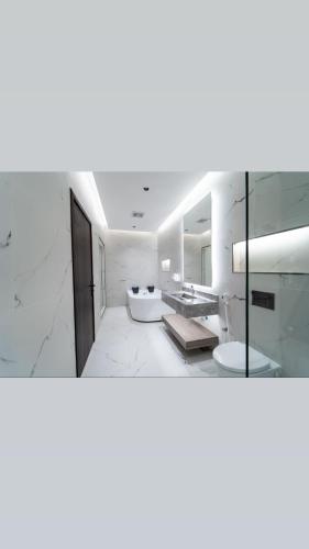 a white bathroom with a sink and a mirror at منتجع ريتال in Dhahran