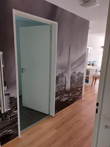 an open door in a room with a painting of a city at Amplio departamento, piso alto, luminoso ! in Buenos Aires