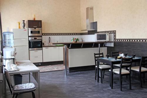 una cocina con electrodomésticos blancos, mesas y sillas en Hostel Saracen on Bolshaya Krasnaya, en Kazán