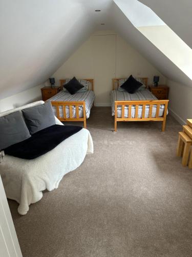 een slaapkamer op zolder met 2 bedden en een trap bij The Barn in South Witham