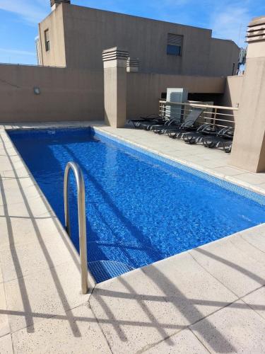 a swimming pool with blue water in front of a building at Excelente Departamento, piso alto in Buenos Aires